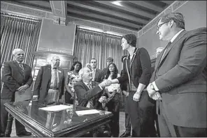  ?? Arkansas Democrat- Gazette/ MITCHELL PE MASILUN ?? Gov. Asa Hutchinson ( center) on Thursday congratula­tes Rep. Jana Della Rosa, R- Rogers, after signing a bill that provides fi nancial help to students pursuing high- demand degrees at public twoyear colleges or technical schools. Della Rosa sponsored the bill.