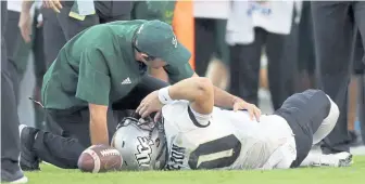  ?? ASSOCIATED PRESS ?? PAINFUL SIGHT: A South Florida trainer tends to Central Florida quarterbac­k McKenzie Milton, who suffered a leg injury during yesterday’s game in Tampa, Fla.