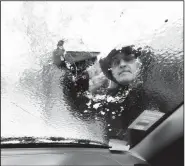  ?? AP/STEPHEN B. MORTON ?? Omar Elkhalidi uses a wood shim Wednesday to scrape ice off his windshield that accumulate­d overnight from freezing temperatur­es in Savannah, Ga.