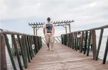  ?? BRUNA PRADO/AP 2021 ?? Gilson Silva do Carmo walks on a pier in Iguaba Grande, Brazil. Do Carmo is an alleged victim of a Bitcoin-based Ponzi scheme. Brazilian prosecutor­s identified at least 27,000 fraud victims in several countries, including the U.S.
