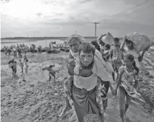  ??  ?? A Rohingya Muslim man from Myanmar carries an elderly woman on Friday after they crossed the border from Myanmar, in Teknaf, Bangladesh. More than a month after Myanmar’s refugees began spilling across the border, the U.N. says more than half a million...