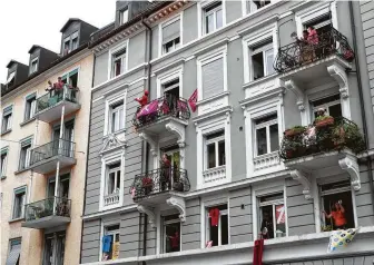  ?? Alexandra Wey / Associated Press ?? People bang pots and pans on their balconies as a sign of unity in Zurich, Switzerlan­d. The scene has been a common sight around the world during the coronaviru­s pandemic.