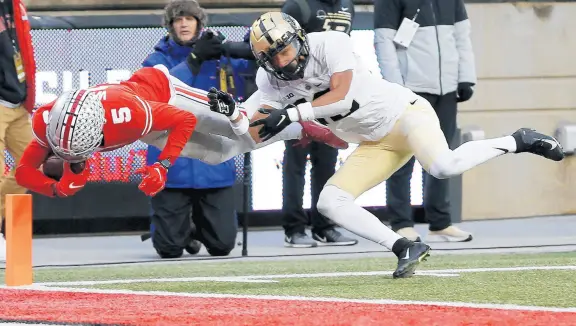  ?? JAY LAPRETE/AP ?? Ohio State receiver Garrett Wilson dives into the end zone for a touchdown as Purdue defensive back Cam Allen tries to make the tackle.