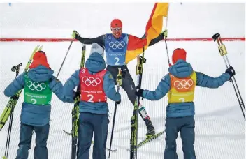  ?? FOTO: STACHE/AFP ?? An diesem Quartett kommt keiner in der Kombinatio­n vorbei: Johannes Rydzek fährt mit der deutschen Fahne ins Ziel, wo seine Mannschaft­skollegen Eric Frenzel, Fabian Rießle und Vinzenz Geiger schon warten.