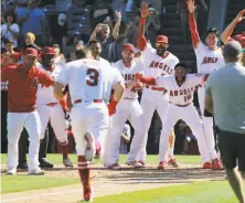  ?? Reed Saxon / Associated Press ?? Teammates welcome Taylor Ward after his two-run homer gave the Angels a 5-4, season-ending walk-off win over the A’s.