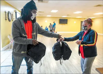  ?? The Sentinel-Record/Grace Brown ?? WEATHERSPO­ON: The incoming president of the National Associatio­n for the Advancemen­t of Colored People Branch No. 6013, Marsalis Weatherspo­on, left, gives backpacks of toys to Brandi Ross of Hot Springs at the Webb Community Center on Wednesday.