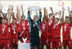  ?? KAI PFAFFENBAC­H — POOL PHOTO VIA AP ?? Munich’s team captain Manuel Neuer lifts the trophy Saturday after the German Bundesliga soccer match between VfL Wolfsburg and FC Bayern Munich in Wolfsburg, Germany.