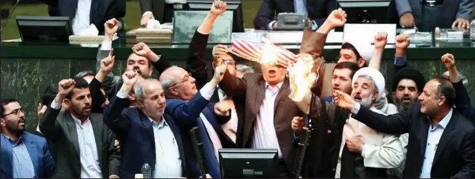 ??  ?? Fiery rhetoric: Agitated members of the Iranian parliament in Tehran burn the US flag yesterday, hours after Donald Trump scrapped the nuclear deal