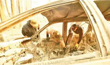  ??  ?? Yuba and Butte County Sheriff officers discover bone fragments inside a burned vehicle in Concow, California after the Camp fire ripped through the area. — AFP photo