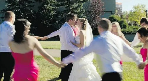  ??  ?? The newlyweds share a kiss as their wedding party dances around them.