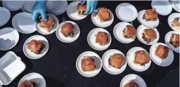  ?? JOEL ANGEL JUAREZ PHOTOS/THE REPUBLIC ?? Martha Castaneda of Arizona Wilderness Brewing Company prepares burgers for patrons to sample during the 14th annual Devour Culinary Classic at the Desert Botanical Garden.