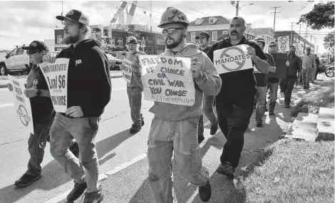  ?? Josh Reynolds / Associated Press ?? Justin Paetow, center, a tin shop worker at Bath Iron Works, takes part in a rally against COVID-19 vaccine mandates on Friday.