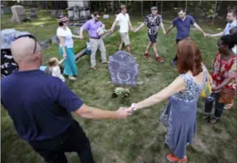  ??  ?? The family of Walter Skold, founder of the Dead Poets Society of America, dance and sing around his grave at the Pine Grove Cemetery in Brunswick, Maine, Monday, Aug. 27, 2018. Skold died of a heart attack at the age of 57 in January 2018, little more than a month after enlisting the son of novelist John Updike to carve a unique grave marker.