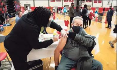  ?? Mark Lennihan / Associated Press ?? Registered nurse Stephenie Champion, left, vaccinates Ramon Soto, 65, on Feb. 10 at Central High School in Bridgeport. The mass vaccinatio­n clinic is one of several ways Bridgeport officials are trying to fight the low vaccinatio­n rates many cities across the country are seeing compared with wealthier suburbs.