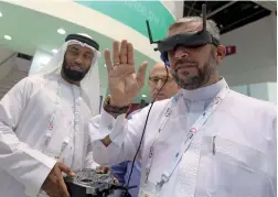  ?? Photos by Dhes Handumon ?? A visitor shakes hand with a robot from Atlab; right, a visitor tries a VR camera for water pipe inspection at the Dewa pavilion at the exhibition. —