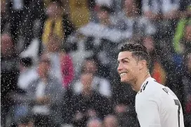  ??  ?? Juventus forward Cristiano Ronaldo looks on through drops of champagne being sprayed as players celebrates securing the team’s eighth straight Italian Serie A championsh­ip, after beating Fiorentina 2-1 at the Juventus Stadium in Turin on Saturday. — AFP