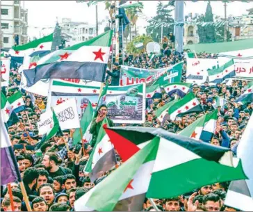  ?? AFP ?? Syrians lift flags during a rally marking 11 years since the start of an anti-regime uprising in Syria’s rebel enclave of Idlib on Tuesday.