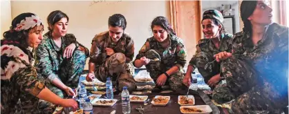  ??  ?? RAQA: Members of the Women’s Protection Units (YPJ) eat on the eastern outskirts of Raqa.