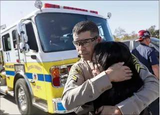  ?? AP PHOTO/MARCIO JOSE SANCHEZ ?? Los Angeles County Deputy Sheriff Armando Viera consoles an unidentifi­ed woman on a freeway overpass after a motorcade with the body of Ventura County Sheriff's Sgt. Ron Helus went by Thursday in Newbury Park, Calif. Helus was fatally shot while responding to a mass shooting at a country music bar in Southern California.