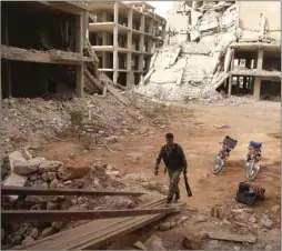  ??  ?? A Syrian rebel-fighter from the National Liberation Front (NLF) enters a building in the rebel-held Al-Rashidin district of western Aleppo’s countrysid­e near Idlib province, yesterday.