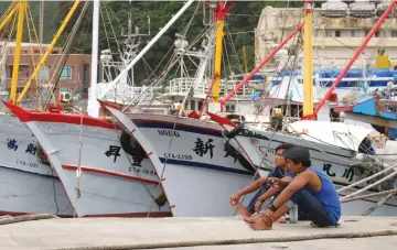  ??  ?? Fishermen rest near boats docked at the Patoutzu Fishing Harbour in Keelung as Typhoon Maria approaches northern Taiwan. — AFP photo