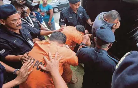  ?? PIC BY ABDULLAH YUSOF ?? Policemen escorting Leading Rate Mohd Farid Musa (front), Leading Rate Mohd Izhrifikri Roslee and Leading Rate Hamzah Zakaria @ Ali out of the Seri Manjung magistrate’s court in Manjung, Perak, yesterday.