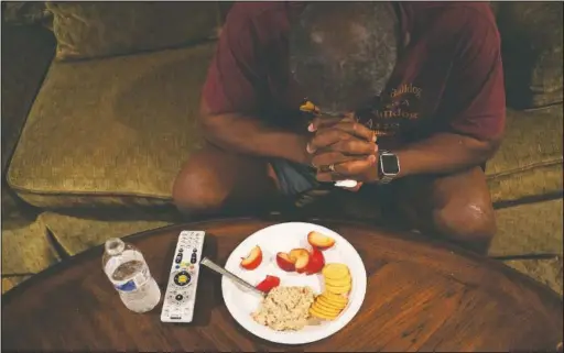  ?? (AP/Wong Maye-E) ?? Mike Bishop prays before his dinner in front of the television in his living room in Byram, Miss.