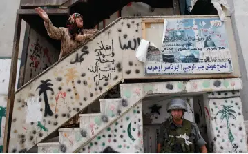  ?? (Reuters) ?? A PALESTINIA­N woman shouts as a border policeman takes up position below her during clashes between Palestinia­n stone-throwers and police in the east Jerusalem neighborho­od of Silwan.