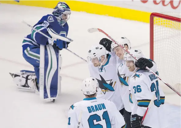  ?? MARK VAN MANEN/PNG ?? Canucks goalie Ryan Miller makes his way back to the net as the San Jose Sharks celebrate Tomas Hertl’s second goal of the game in the first period of Sunday’s contest at Rogers Arena. The Canucks lost 3-1, their ninth defeat in their last 11 outings.