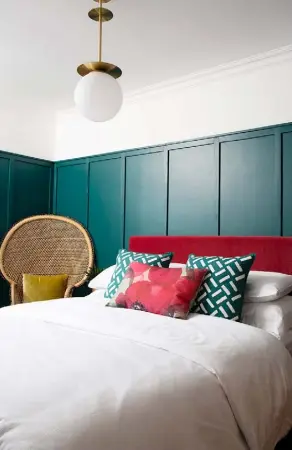  ??  ?? MAIN BEDROOM
MDF panelling painted in Green Marble by Valspar adds character, as does the dark pink velvet headboard, made by the couple. ‘I have an obsession with high beds, as it feels like you’re staying in a hotel room,’ says Chris. ‘It also provides much-needed storage drawers.’ The peacock chair was a £35 bargain on Facebook