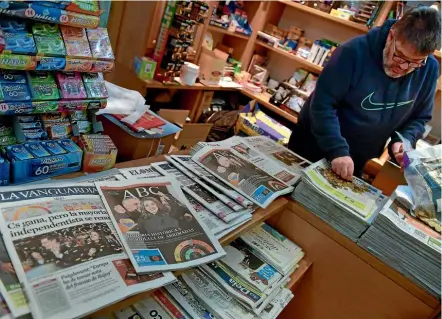  ??  ?? A shopkeeper in Pamplona, northern Spain counts coins next to Spanish newspapers featuring the results of the Catalan regional election. The vote failed to clarify the restive region’s immediate future.