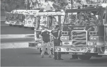  ?? ANDY ALFARO, THE MODESTO BEE, VIA AP ?? Firefighte­rs gather Thursday in Tuolumne City, Calif., one of two key staging points for the Rim Fire. The blaze was 30% contained Thursday, thanks to cooler, wetter weather in the area.