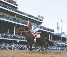  ?? TIM NWACHUKWU/ GETTY IMAGES ?? Medina Spirit, ridden by jockey John Velazquez, crosses the finish line to win the Kentucky Derby at Churchill Downs in Louisville, Ky., last weekend, before 52,000 fans in the stands.