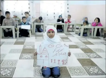  ?? UMIT BEKTAS/REUTERS ?? Syrian refugee Islem Halife, 11, shows a drawing of her home in Syria, as she sits in a classroom where she learns the Quran in Nizip refugee camp in Gaziantep province, Turkey.