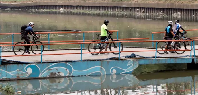  ?? PHOTOGRAPH BY ANALY LABOR FOR THE DAILY TRIBUNE@tribunephl_ana ?? BIKERS cross a bridge while keeping distance from one another as the rate of Covid-19 infection remains high in the country.