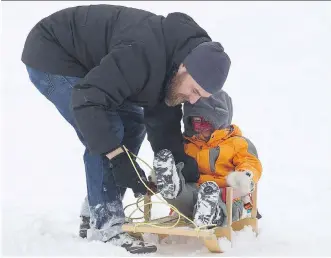  ?? IAN KUCERAK/FILES ?? A father and son get ready to go up the toboggan hill at a park in Edmonton. The value of play for both children and adults is too often overlooked, writes Peter Nieman.