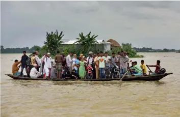  ?? — AP ?? Flood affected villagers commute to safer places using a boat at Morigaon district in Assam on Tuesday.