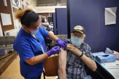  ?? Scott Olson, Getty Images ?? Lalain Reyeg administer­s a COVID-19 booster vaccine and an influenza vaccine to Army veteran William Craig at the Edward Hines Jr. VA Hospital on Friday in Hines, Ill.