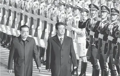  ?? — Gambar Reuters ?? DIBERI PENGHORMAT­AN: Li (kiri) mengiringi Abe memerika barisan kehormat ketika kedua-dua pemimpin itu menghadiri majlis sambutan di luar Dewan Agung Rakyat di Beijing, China semalam.