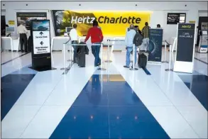  ?? Bloomberg News/LUKE SHARRETT ?? Customers wait in line at a Hertz Global Holdings Inc. rental location inside Charlotte Douglas Internatio­nal Airport in Charlotte, N.C., in February.