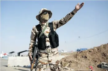  ?? Dan Kitwood/Get ty Images ?? A peshmerga fighter directs traffic at a Kurdish checkpoint Saturday in Kalak, Iraq. As fighting rages throughout the country, Kurds in the north are asserting their independen­ce.