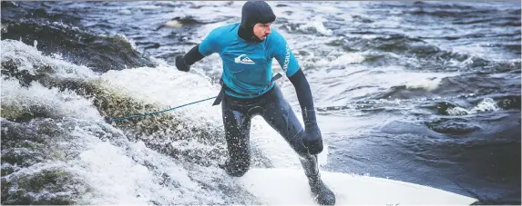  ?? ASHLEY FRASER FILES ?? Brett Painter from River-Surf Ottawa Gatineau surfs the Ottawa River near Parc Brébeuf in January. What is the river's original Algonquin name?