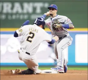  ?? John Fisher / Getty Images ?? The Mets’ Javier Baez turns a double play in the seventh inning against the Brewers on Saturday.