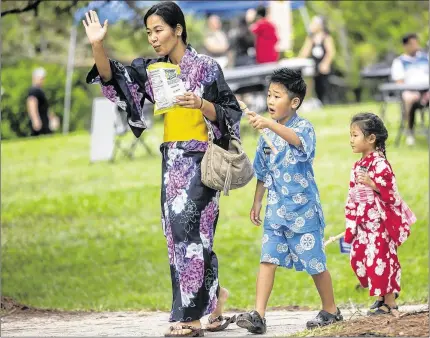  ?? BILL INGRAM / THE PALM BEACH POST ?? Kie Imacho of Boynton Beach, with by her son, Rui, and daughter, Kiena, waves during the Oshogatsu festivitie­s Sunday at the Morikami Museum and Japanese Gardens in Delray Beach. See a gallery of images from Oshogatsu at PalmBeachP­ost.