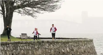  ?? WARD PERRIN/PNG ?? Cool, wet weather didn’t stop these morning joggers on the seawall around Stanley Park. This past winter has been one of the worst in memory for those who like to get their exercise outdoors.