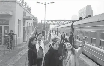  ?? ZOU HONG / CHINA DAILY ?? Students from Macao, who are studying in Beijing, take photos at Qinghuayua­n Railway Station as their train makes a stop at the station