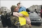  ?? ?? A SOLDIER gets a hug from Yuliya Voitu, 13, wrapped in a Ukrainian f lag that troops had signed.