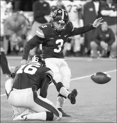  ?? CHARLIE NEIBERGALL/THE ASSOCIATED PRESS ?? Iowa’s Keith Duncan kicks a 33-yard field goal out of the hold of punter Ron Coluzzi on the final play, giving the unranked Hawkeyes a 14-13 victory over No. 2 Michigan on Saturday at Iowa City.