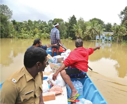  ?? Aijaz Rahi/Associated Press ?? ■ Volunteers travel in a boat with essential supplies for stranded people Sunday in a flooded area in the southern state of Kerala, India.