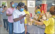  ??  ?? Migrant workers line up to receive gift bags from volunteers of ItsRaining­Raincoats.